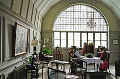 two people are sitting at a table in an ornately decorated room with high arched windows