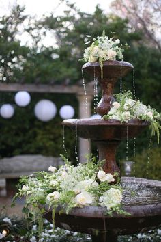 three tiered water fountain decorated with flowers and greenery