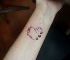 a dog paw and heart tattoo on the wrist with pink flowers in front of it