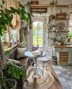 a kitchen filled with lots of potted plants next to a table and chairs in front of a window