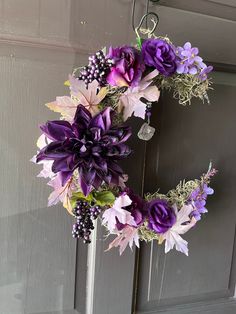 a wreath with purple flowers hanging on a door