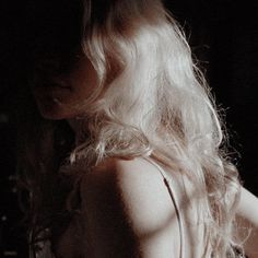 a woman with long blonde hair standing in the dark