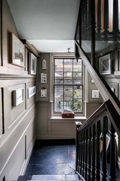 the stairs in this house have pictures hanging on them and framed with black iron railings