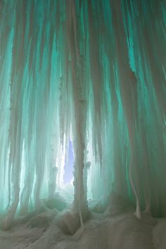 the inside of an ice cave with snow on the ground and icicles hanging down