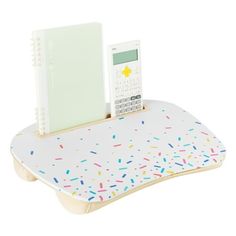 a desk with a cell phone on it and a notepad holder in the shape of a tabletop