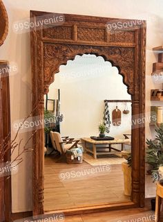 an ornate wooden mirror in the middle of a room with furniture and decorations around it