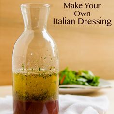 a bottle filled with olive oil sitting on top of a table next to a plate