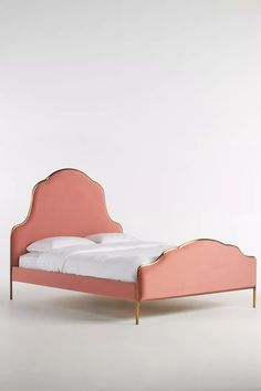 a pink bed frame with white sheets and pillows on it, against a white background