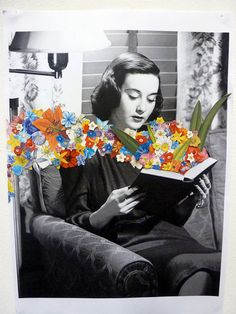 a woman sitting in a chair reading a book with flowers on the cover and behind her