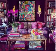 a living room filled with lots of purple furniture and bookshelf full of books