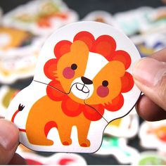 a hand holding a sticker with an image of a lion on it's face