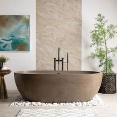 a bath tub sitting on top of a white floor next to a painting and potted plant