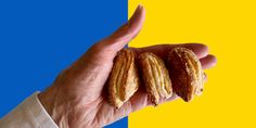 a hand holding three almonds in front of a blue and yellow background