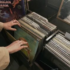 a person reaching for a record in front of a stack of records