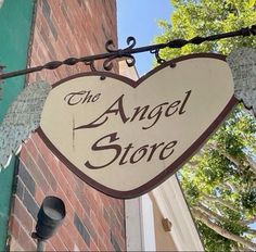 the angel store sign is hanging from a wire near a brick wall and street light