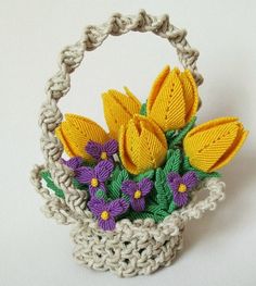 a crocheted basket with yellow and purple flowers in it on a white surface