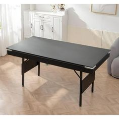 a black table sitting on top of a hard wood floor next to a gray chair