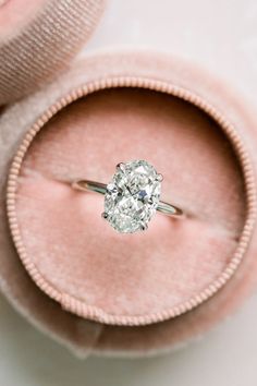 an engagement ring in a pink velvet box with a diamond center stone on the side