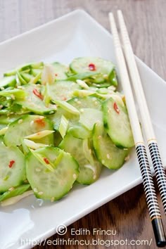 a white plate topped with cucumbers and chopsticks