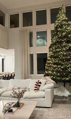 a living room filled with furniture and a christmas tree in front of a large window