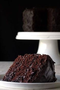 a slice of chocolate cake on a white plate next to the rest of the cake