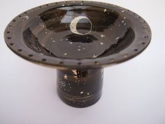 a black vase with stars on it and a moon in the center, sitting on a white surface