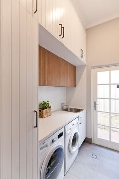 a washer and dryer in a small room with white tile flooring on the walls