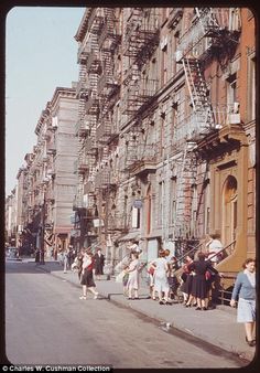 people are standing on the sidewalk in front of an old building