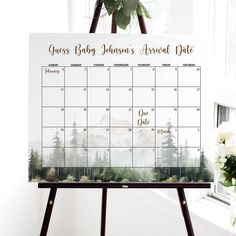 a desk calendar on a easel next to a vase with flowers and greenery