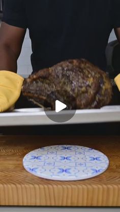 a man is cooking a large piece of meat on a pan with yellow cloths