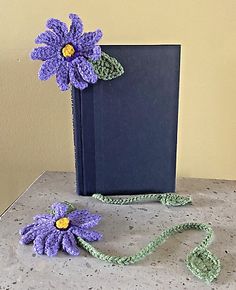 a crocheted book and flower on a table