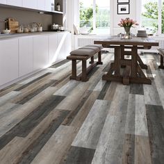 a kitchen with white cabinets and wood flooring in the dining room, along with a wooden table surrounded by benches