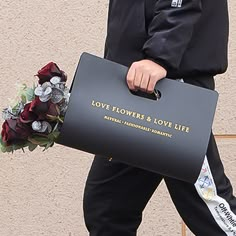 a man walking down the street carrying a bag with flowers and love written on it