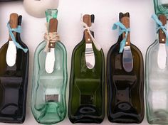 four empty wine bottles tied together with twine and rope, lined up against a white wall