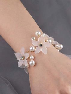 a close up of a person's hand wearing a bracelet with flowers and pearls