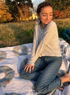 a young woman sitting on top of a quilt