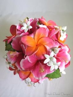 a bouquet of pink and orange flowers on a white table cloth with green leaves in the center