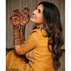 a woman is smiling and holding her hands up to show the henna designs on her hand