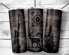 three wooden tumblers with different designs on them, one has a deer and the other is an arrow