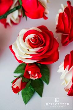 several red and white roses are arranged on a table with one flower in the middle