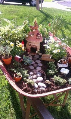 a wheelbarrow filled with lots of plants and small houses on top of it