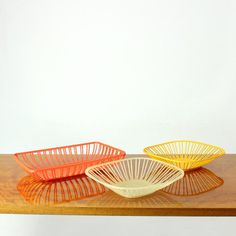 three bowls sitting on top of a wooden table next to each other in different colors