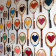 many different types of tennis racquets are arranged on a wall with hearts