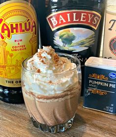 there is a drink with whipped cream in the glass next to some liquor bottles on the table