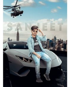 a man sitting on top of a sports car in front of a helicopter flying overhead