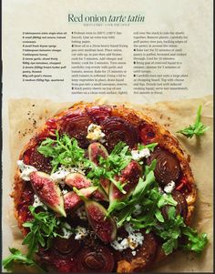 a pizza topped with figs and greens on top of a piece of parchment paper