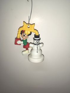 a christmas ornament with a snowman and a star hanging from it's side