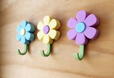 three flower shaped hooks are hanging on the wall