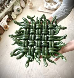 a person holding a green woven object in their hands