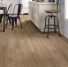 a kitchen with wooden floors and white walls, two bar stools on the counter